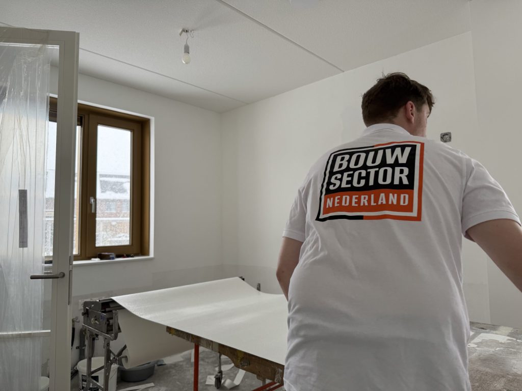 Behanger van Bouwsector Nederland legt een baan behang klaar op de plaktafel